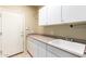 Well-lit laundry room equipped with white cabinets, sink, and ample countertop space at 2551 E Buena Vista Pl, Chandler, AZ 85249
