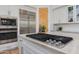 Close-up of the kitchen cooktop featuring stainless steel appliances, white cabinets, and stone countertops at 27171 N 73Rd St, Scottsdale, AZ 85266