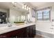 Bathroom featuring dual sinks, a bathtub, and a large mirror at 3438 E Betsy Ln, Gilbert, AZ 85296