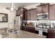 The kitchen has dark wood cabinets, an island with a granite counter, and a stainless steel fridge and range at 3438 E Betsy Ln, Gilbert, AZ 85296