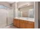 Bathroom with double sink vanity, shower stall with glass doors, and a large mirror at 6460 S Springs Pl, Chandler, AZ 85249