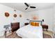Bright bedroom with a ceiling fan, decorative hats, and a comfortable queen-sized bed with orange pillows at 6729 E Sharon Dr, Scottsdale, AZ 85254