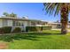 Well-kept front yard featuring lush green grass, trimmed hedges, and a mature shade tree at 10750 W Abbott Ave, Sun City, AZ 85351