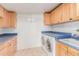 Laundry room with front loading washer/dryer, blue countertops, wood cabinets, and a utility sink at 10750 W Abbott Ave, Sun City, AZ 85351