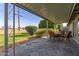 Covered outdoor patio with stone flooring and comfortable seating overlooking the lawn at 10750 W Abbott Ave, Sun City, AZ 85351