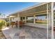 Covered outdoor patio with stone flooring and comfortable seating overlooking the lawn at 10750 W Abbott Ave, Sun City, AZ 85351