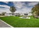 Large backyard with lush artificial grass, an outdoor kitchen, a fireplace, and a view of the modern home at 12209 N 66Th St, Scottsdale, AZ 85254