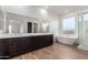 Bathroom featuring a soaking tub, glass shower, double sink and wood-look flooring at 13653 W Crabapple Dr, Peoria, AZ 85383