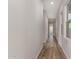 Long hallway features wood flooring, neutral walls, natural light from windows, and access to various rooms at 13653 W Crabapple Dr, Peoria, AZ 85383