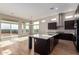 Open-concept kitchen featuring an island with a sink, dark cabinets, stainless appliances, and outdoor access at 13653 W Crabapple Dr, Peoria, AZ 85383