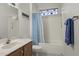 Cozy bathroom featuring a bathtub, shower curtain, a wooden vanity, a sink, and a towel rack at 15848 W Lahlum Ln, Surprise, AZ 85374