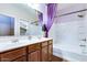 Bright bathroom featuring a double sink vanity with wood cabinets and a shower-tub combination with a purple curtain at 16026 N 171St Ln, Surprise, AZ 85388