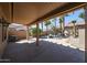 Expansive covered patio with ample space for seating and dining, complemented by desert landscaping and mature trees at 16137 W Quail Creek Ln, Surprise, AZ 85374
