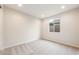 Vacant bedroom with neutral carpet and walls, large window, base molding, and a two-prong outlet at 16721 W Whispering Wind Dr, Surprise, AZ 85387