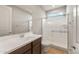 Modern bathroom with a glass-enclosed shower, and a single sink vanity with brown cabinets at 16735 W Whispering Wind Dr, Surprise, AZ 85387