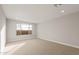A bright bedroom with neutral walls, carpet flooring, recessed lighting, and a large window overlooking the landscape at 16735 W Whispering Wind Dr, Surprise, AZ 85387