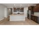 A kitchen with a large island with granite countertop, stainless steel appliances, and dark wood cabinets at 16735 W Whispering Wind Dr, Surprise, AZ 85387