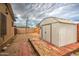 View of the backyard with a tool shed on wooden platform, gravel ground, and fencing at 17841 N 20Th St, Phoenix, AZ 85022