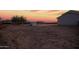 Backyard at sunset with neutral colored land, small shed, and desert landscaping at 1819 W Joy Ranch Rd, Phoenix, AZ 85086