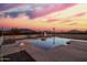 A view of the pool at sunset, with a diving board and surrounding gravel at 1819 W Joy Ranch Rd, Phoenix, AZ 85086