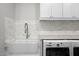 Close-up of the laundry room's modern washer and dryer, stylish sink, and tiled backsplash at 280 W Wisteria Pl, Chandler, AZ 85248