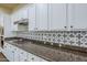 A kitchen counter features granite countertops, white cabinets, and a decorative backsplash, creating a luxurious space at 32742 N 15Th Gln, Phoenix, AZ 85085