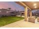 This covered patio overlooks the backyard which includes an outdoor kitchen, hot tub, and lush green grass at 3840 W Brogan Ct, New River, AZ 85087