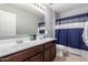 Bright bathroom featuring dual sinks, a large mirror, cabinet storage and shower curtain at 3840 W Brogan Ct, New River, AZ 85087