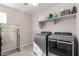 Bright laundry room with modern washer and dryer, a hanging rack, and storage shelf at 3840 W Brogan Ct, New River, AZ 85087