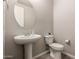 Simple powder room featuring a pedestal sink, round mirror, and efficient toilet at 3840 W Brogan Ct, New River, AZ 85087