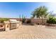 Desert landscaped backyard featuring a built-in grill, cactus, and stone patio, offering a unique outdoor space at 583 W Bismark St, San Tan Valley, AZ 85143