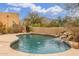 Backyard pool featuring rock waterfall feature, lush desert landscaping, and mountain views at 10955 E Vista Del Cielo Rd, Gold Canyon, AZ 85118