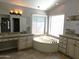 Bathroom featuring a soaking tub, dual vanities, and a large window for natural light at 1119 E Southshore Dr, Gilbert, AZ 85234