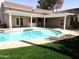 An in-ground pool is surrounded by lush grass and a covered patio in the backyard, providing shade at 1119 E Southshore Dr, Gilbert, AZ 85234