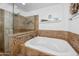 Relaxing bathroom with a large tub, separate glass enclosed shower, and tiled walls at 11820 S Half Moon Dr, Phoenix, AZ 85044