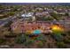 Aerial view of an impressive estate featuring a pool, fire pit, and sport court at dusk at 12980 E Cochise Rd, Scottsdale, AZ 85259