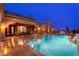 Expansive backyard with a pool, patio dining set, and lounge area at dusk at 12980 E Cochise Rd, Scottsdale, AZ 85259