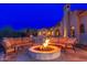 Outdoor seating around a stone fire pit with a backyard view at dusk at 12980 E Cochise Rd, Scottsdale, AZ 85259