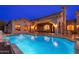 Luxury backyard with a large pool and patio dining at dusk at 12980 E Cochise Rd, Scottsdale, AZ 85259