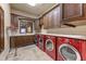 Well-lit laundry room featuring red front-loading washer and dryer set and custom cabinetry for ample storage at 14371 E Kalil Dr, Scottsdale, AZ 85259