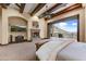 Spacious main bedroom with a fireplace, beamed ceilings, and balcony access with stunning views at 14371 E Kalil Dr, Scottsdale, AZ 85259