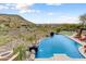 Stunning infinity-edge pool with desert views and a cascading waterfall, creating a serene oasis at 14371 E Kalil Dr, Scottsdale, AZ 85259