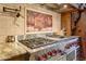 Professional grade stainless steel range with red knobs and detailed tile backsplash at 14371 E Kalil Dr, Scottsdale, AZ 85259