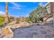 Landscaped backyard featuring stone patio, rock waterfall feature, and mature trees for relaxing outdoor enjoyment at 16014 W Kino Dr, Surprise, AZ 85374