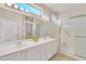 Bright bathroom featuring double sinks, sleek cabinetry, and a modern glass-enclosed shower at 16014 W Kino Dr, Surprise, AZ 85374