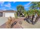 Well-maintained front yard with gravel ground cover, palm trees, barrel cactus and green shrubbery at 16014 W Kino Dr, Surprise, AZ 85374