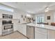 Sunlit kitchen with stainless steel appliances, white cabinets, and a view of the dining area at 16014 W Kino Dr, Surprise, AZ 85374