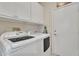 Well-lit laundry room with washer, dryer, cabinets and a door at 16014 W Kino Dr, Surprise, AZ 85374