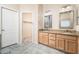 Bathroom with double sinks, granite countertops, wooden cabinets, and a walk-in closet at 17768 W Maui Ln, Surprise, AZ 85388