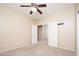 Comfortable bedroom with neutral carpet, a ceiling fan, and double doors leading to the walk-in closet at 17768 W Maui Ln, Surprise, AZ 85388